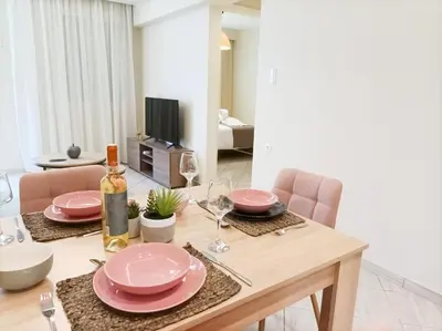 a dining table with pink plates and a bottle of wine at Amelie Apartment in Palaiochóra