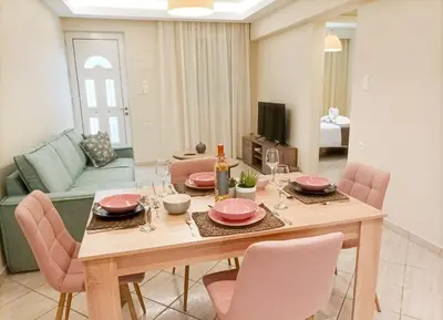 a dining room with a wooden table and pink chairs at Amelie Apartment in Palaiochóra