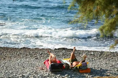 two people laying on a beach near the water at History & Culture in Old Town Chania in Chania Town