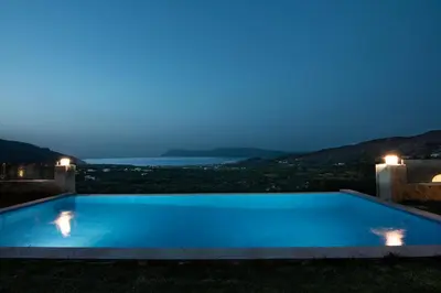 a swimming pool at night with the ocean in the background at Villas Libra in Falasarna