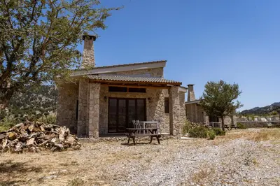 a stone house with a picnic table in front of it at Omalos Village in Omalós