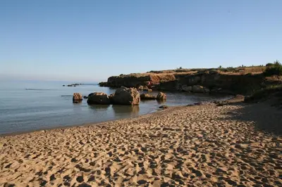 a sandy beach with rocks in the water at Flamingos Hotel Apartments in Kato Daratso