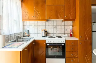 a kitchen with wooden cabinets and a white stove top oven at Peggy's apartment in Chania in Chania Town