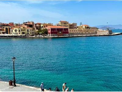 a group of people walking on a sidewalk next to a body of water at Tersanas Beach Apartments in Chorafakia