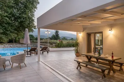 a patio with a table and chairs and a pool at Villa Nature, Heated Pool in Kalyves
