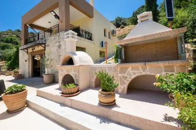 a house with a courtyard with potted plants in front of it at Villa Leon in Souda