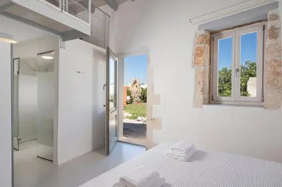 a white bedroom with a bed and a window at Tholos Cottage in Stérnai