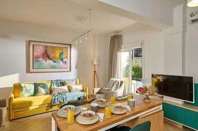 a living room with a yellow couch and a table at KaiZen Chania - New Central Apartment Just 350m Away With Private Jacuzzi and free parking! in Chania Town