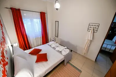 a bedroom with a white bed with red curtains at Popi's House in Chania Town