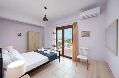 a bedroom with a bed and a table and a window at Villa Stratianna by PosarelliVillas in Módhion