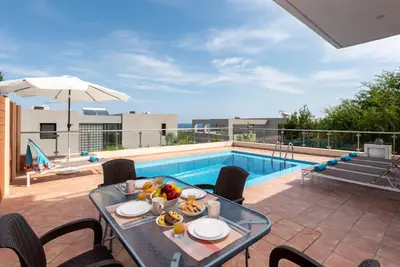 a table with food on it next to a swimming pool at Villa Flora by PosarelliVillas in Módhion