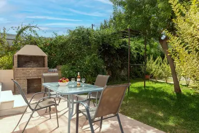 a patio with a table and chairs and a fireplace at Villa Flora by PosarelliVillas in Módhion
