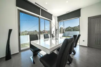 a dining room with a white table and black chairs at La Maison Du Soleil Luxury Villa by 8essentially in Varípetron