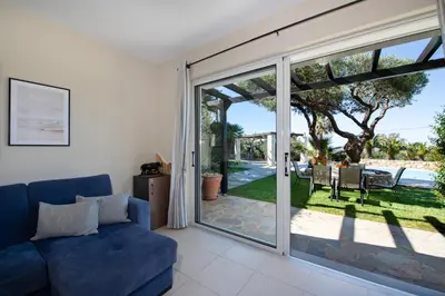 a living room with a blue couch and a sliding glass door at Gabriel apartment with a shared pool close to the beach in Chorafakia