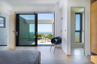 a bedroom with a view of a balcony at Avra & Ostria Villa, Pirgos-Villas,Heated pool , amazing sea view in Maleme