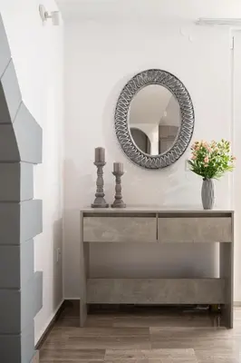 a console table with a mirror and a vase of flowers at OLIVE ANGEL in Chania Town