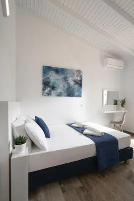 a white bedroom with a large bed with blue pillows at OLIVE ANGEL in Chania Town