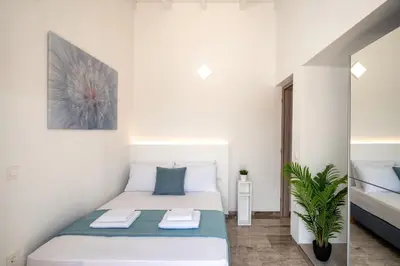 a small bedroom with a white bed and a plant at OLIVE ANGEL in Chania Town