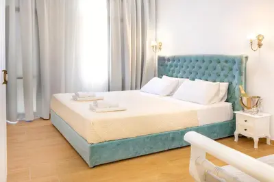 a bedroom with a large bed with a blue headboard at Vener Suites in Chania Town