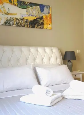 a white bed with two towels on top of it at Odyseia Apts ΙI at the Center of the City & Old Town in Chania Town
