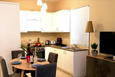 a kitchen with a table with chairs and a kitchen with white cabinets at Odyseia Apts ΙI at the Center of the City & Old Town in Chania Town
