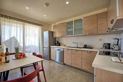 a kitchen with wooden cabinets and a table with a bowl of fruit at Phaedra by PosarelliVillas in Kounoupidhianá