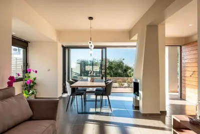 a living room with a couch and a table and chairs at Phaedra by PosarelliVillas in Kounoupidhianá