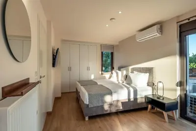 a bedroom with a large bed and a mirror at Phaedra by PosarelliVillas in Kounoupidhianá