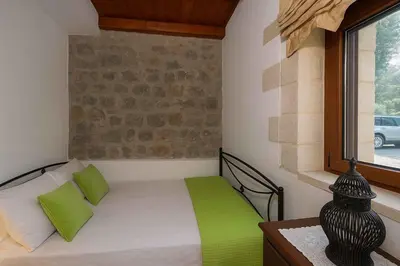 a bedroom with a bed with green pillows and a window at Geroulios Kastro Villas I 