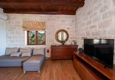 a living room with a couch and a flat screen tv at Geroulios Kastro Villas I 
