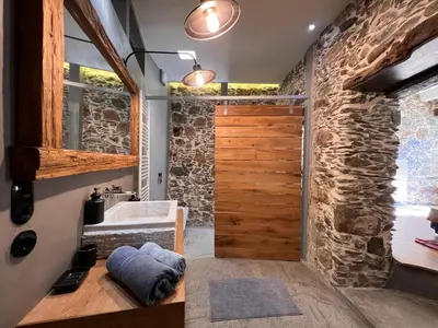 a bathroom with a stone wall and a wooden door at The Stone House in Avdhoulianá