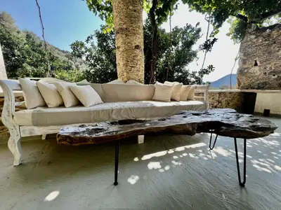 a white couch sitting on a patio with a coffee table at The Stone House in Avdhoulianá