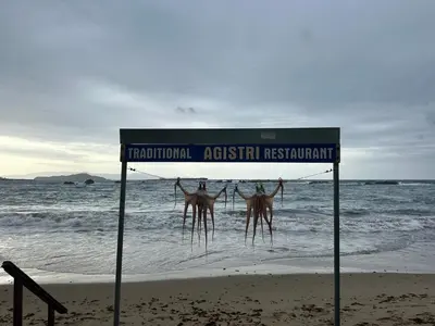 a sign on the beach next to the ocean at W Apartment in Chania Town