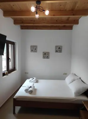 a bedroom with a white bed with a wooden ceiling at Alexander's cottage in Límni