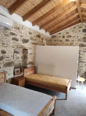 a bedroom with two beds in a stone wall at Alexander's cottage in Límni