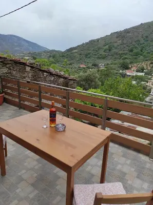 a wooden table with a bottle and two glasses on it at Alexander's cottage in Límni