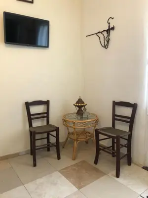 two chairs and a table and a tv on a wall at ARETI Sea View Mountain Cottage in AmigdhalokeFálion