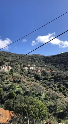 a view of a hill with trees and houses on it at ARETI Sea View Mountain Cottage in AmigdhalokeFálion