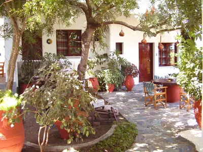 a patio with chairs and trees and a building at Summer Lodge in Maleme