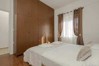 a bedroom with a white bed and a wooden cabinet at Vasiliki house in Daratso