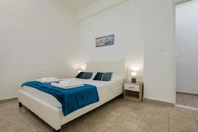 a white bedroom with a bed and a night stand at Vasiliki house in Daratso