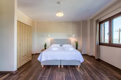 a bedroom with a bed with white sheets and wooden floors at Apokoronas Views Villa in Néon Khoríon