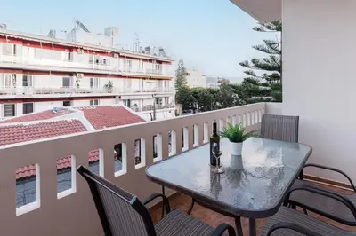 a table and chairs on a balcony with a bottle of wine at Nostos Central Apartment in Chania Town