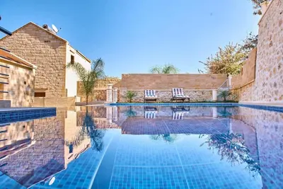 a swimming pool with two chairs sitting next to a building at Sunaktis luxury villa in Chania Town