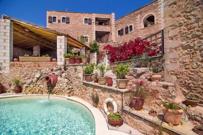 an outdoor swimming pool in a stone building with potted plants at Samonas Traditional Villas in Samonás