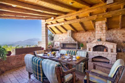 a patio with a table and a stone fireplace at Samonas Traditional Villas in Samonás