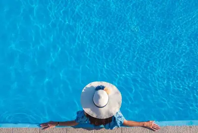 a person with a hat sitting in a swimming pool at Villa Malaxa Private Luxury with Amazing View in Maláxa