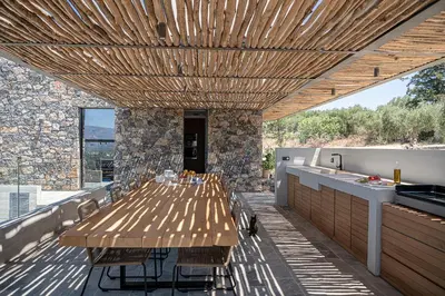a large wooden table on a patio with a kitchen at Brand new Villa Eleftheria BY APOKORONAS-VILLAS in Plaka