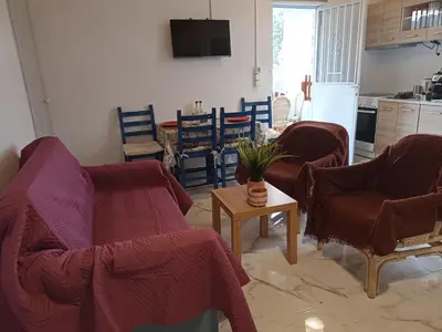 a living room with couches and chairs and a kitchen at Chania Mini Villas in Skinés