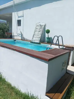 a swimming pool with a wooden deck next to a house at Chania Mini Villas in Skinés